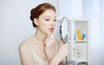 Young woman looking at her gums in mirror