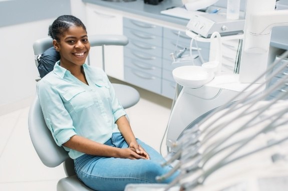 Woman smiling in dental chair before guided tissue bone regeneration in Clute