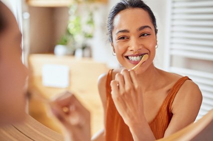 Woman smiling while brushing her teeth