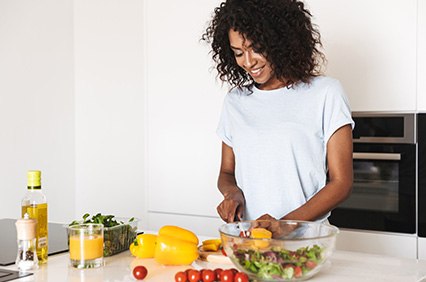 Smiling woman preparing salad in kitchen