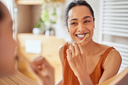 Woman smiling while brushing her teeth