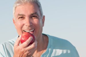 Older man biting into an apple