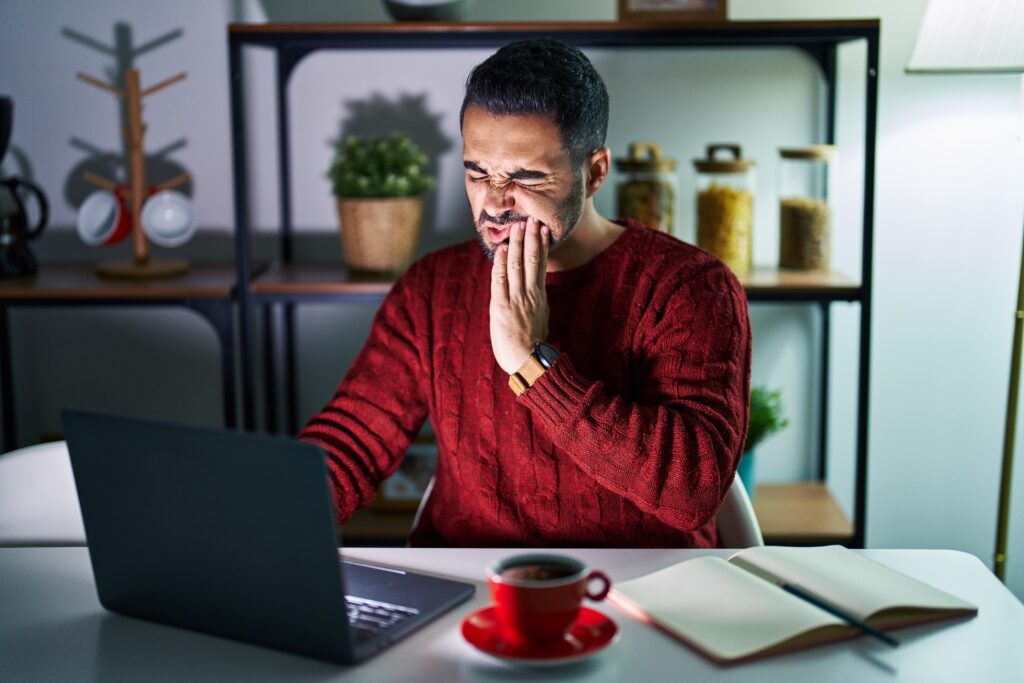 Man experiencing toothache while working at night